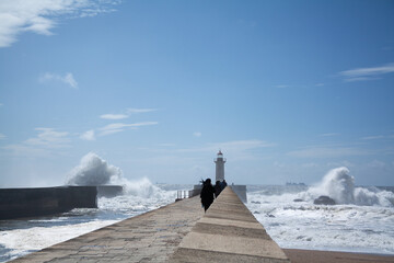 Several unrecognizable tourists walk along the pier to the Felgueiras Lighthouse in Porto Portugal....