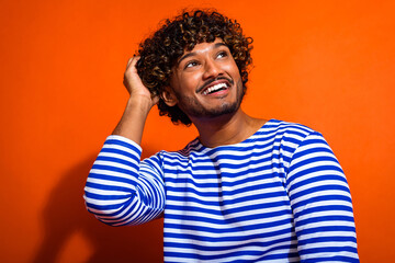 Young man in striped sailor shirt posing against vibrant orange backdrop showcasing cheerful and...