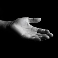 A grayscale close-up of an open hand, palm facing forward, against a black background.  The hand's details are visible, showing texture and form