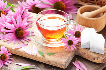 Echinacea purpurea vitamin tea or extract on wooden background with fresh flowers nearby, copy space, natural medicine, antiviral treatment, immune booster concept