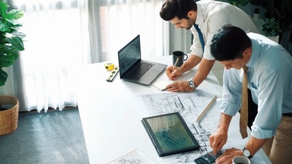 Top view of manager talk and discussing about house construction while sit and write at blueprint...