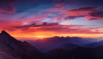 Obraz premium A Striking Sunset Over A Mountain Landscape The Sky Is Bathed In Vibrant Hues Of Orange And Pink Creating An Atmospheric Glow That Contrasts With The Deepening Blue Of The Sky Above