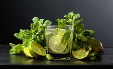 Mojito with ice, lime, and mint on a black background.