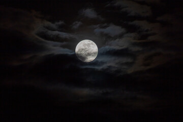 Full moon in the night sky with dark clouds, 