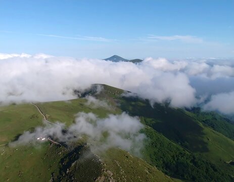 High-altitude view of rolling green mountains shrouded in white clouds