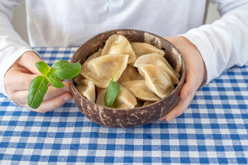 Dumplings in coconut bowl in the hands of a child.