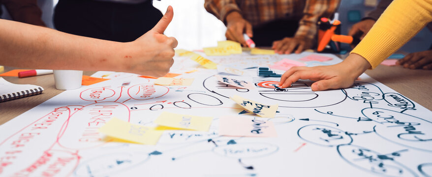 A dynamic brainstorming session featuring diverse hands working collaboratively on colorful sticky notes and charts, fostering creative ideas in a modern office backdrop. SACTR