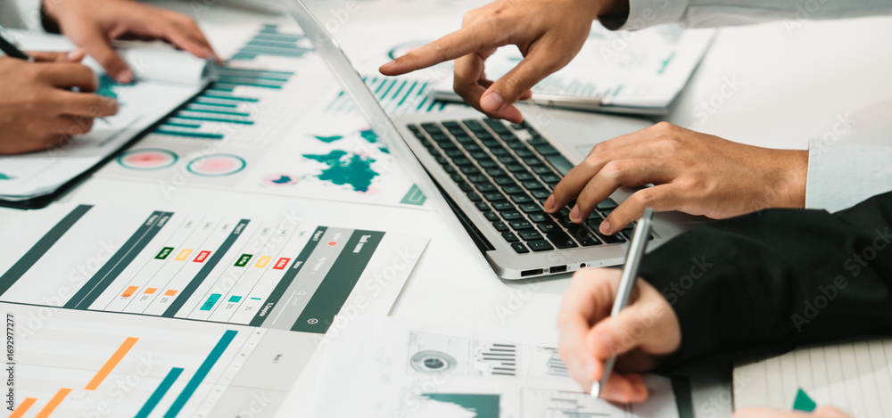Poster a team actively engaged in a business meeting focused on data analysis, utilizing a laptop and vario