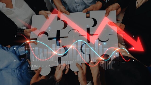 A diverse group collaborates over puzzle pieces while charts display a decline, representing strategic problem-solving and innovative teamwork in a business environment. Raster - Powered by Adobe