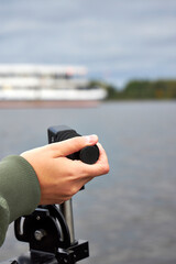 Fisherman steering boat while looking at fishfinder screen on a lake. Modern angling technology with echo sounder and scenic river view. Fishing, navigation, and outdoor recreation concept