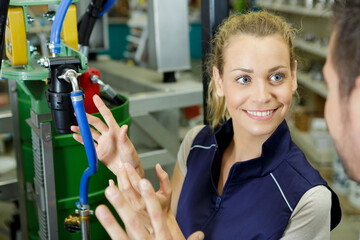 female worker showing hose on machinery to colleague