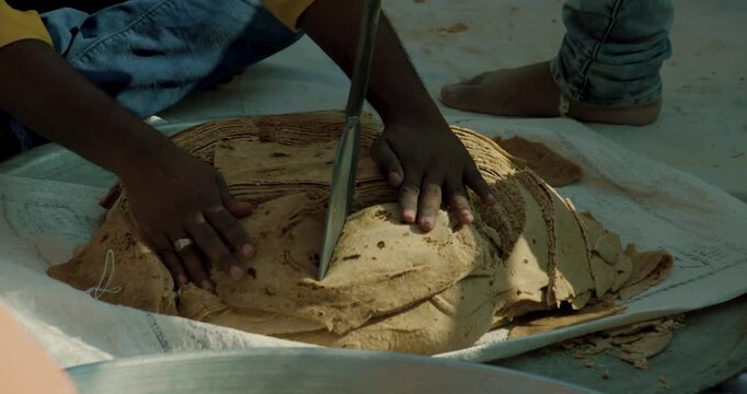 Traditional Indian Community Preparing Giant Sacred Flatbreads for Spiritual Festival &ndash; Kneading Dough, Roasting, and Cutting Large Roti During Ritual Celebration