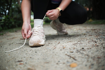 Closeup hand of athletes female tying the shoes laces during her running trail