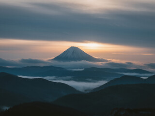 Fototapeta premium Scenic view of a majestic mountain peak surrounded by clouds during sunrise. Beautiful natural landscape ideal for concepts of travel, adventure, nature, inspiration, and outdoor exploration.