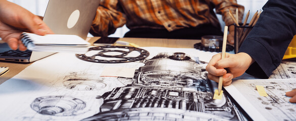 A dynamic team of engineers engages in a detailed brainstorming session, working on technical drawings and sketches of machinery in a modern office environment. SACTR