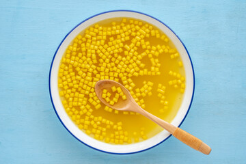 Bowl of chicken broth served with mini croutons over blue wooden background. Top view.
