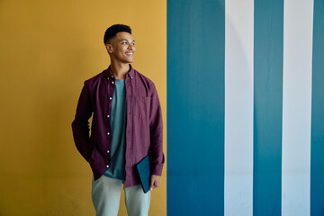 Fototapeta premium Smiling young businessman in smart casual with tablet standing against wall in office