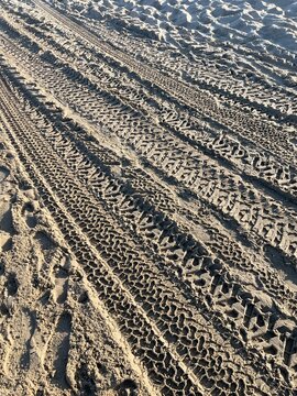 Many parallel tire tracks in the sand 