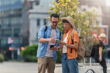 Tourists in their forties using a map and smartphone to plan a city sightseeing trip, enjoying...