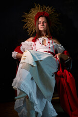 Fototapeta premium Mysterious woman in ethnic attire sitting regally against a dark backdrop, radiating a sense of ancient power and cultural richness in striking white and red