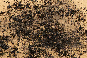 Scattered coal chips and dust on brown cardboard as texture