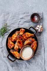 Grilled spicy chicken wings with ketchup in a plate on a light slate, stone or concrete background. Top view with copy space.