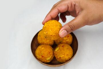 Navaratri ladoo or laddu. Indian woman hand taking yellow ladoo. Indian festival food snack, sweet Lohri Pongal, Diwali, Ganesh Chaturthi, Navaratri, Indian festival concept.