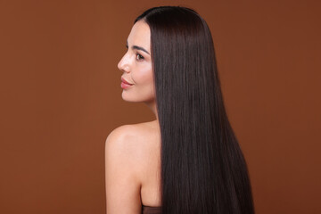 Woman with beautiful smooth hair after lamination procedure on brown background