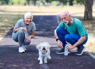 Portrait of a happy active beautiful senior woman and man couple with htheir pet dog outdoors