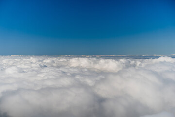 Mid-Air cloudscape. A serene minimalist scene of soft, rolling cloudscape beneath a clear blue sky.