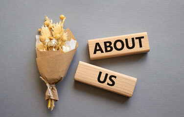 About us symbol. Concept word About us on wooden blocks. Beautiful grey background with bouquet of...
