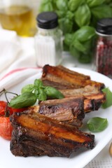 Roasted beef ribs, tomatoes and spices on table, closeup