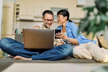 Portrait of a lovely young couple using a laptop and a mobile phone  together and having fun...