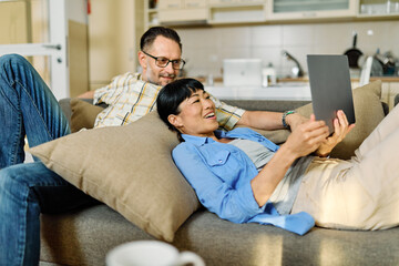 Portrait of a lovely young couple using a laptop together and having fun sitting on sofa at home