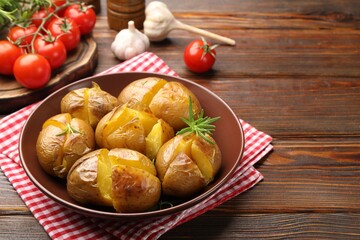 Tasty baked potatoes with rosemary served on wooden table, space for text