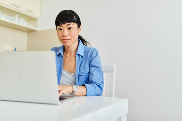 Portrait of a young asian woman girl using laptop and mobile phone  at home