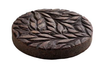Artisanal round black tea cake featuring a detailed carved leaf motif.