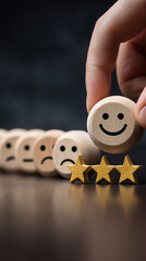 Person's hand placing a happy face wooden token above three golden stars in a row of emoji faces customer feedback