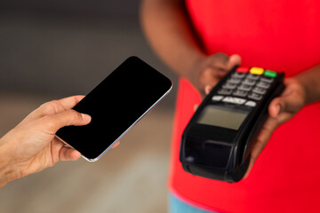 Woman paying for purchases using modern easy nfc technology, holding smartphone with empty blank screen in hand closeup. Card reader machine making payment transaction with cashless contactless method