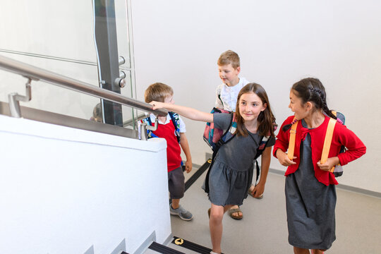 Children with backpacks climbing stairs at school.