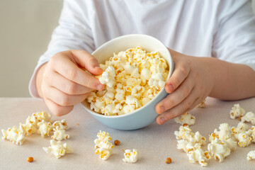 Bowl of popcorn in the hands of a child.