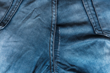 Fototapeta premium Close-up of blue denim jeans with pocket textures and seam details and broken buttons visible.