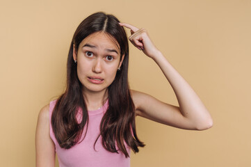 Fototapeta premium Young woman expresses confusion while standing against a neutral background in a casual setting