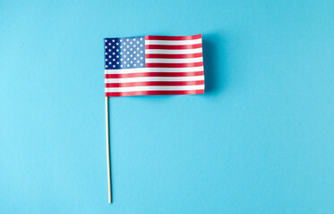 Miniature American flag on clean blue background emigration concept