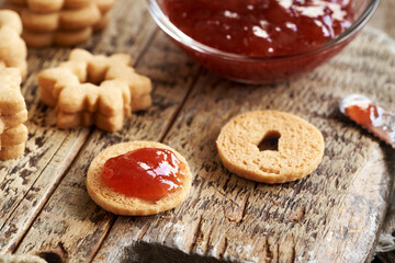 Filling homemade Linzer Christmas cookies with strawberry marmalade