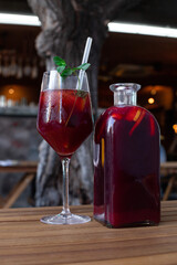 Spanish sangria served in a beautiful glass and a clear pitcher on a wooden table at an outdoor café