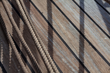Nautical background and textures. Vintage sailing environment. Coils of thick, twisted rope across wooden deck, casting shadows. 