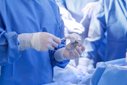 Surgeon applying bone cement to knee implant during arthroplasty