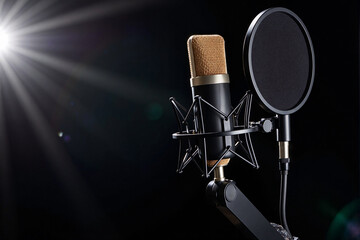 Professional golden studio condenser microphone with pop filter ready for recording music or a podcast against a dark background with lens flare