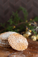 Pizzelles Sprinkled with Powdered Sugar on a Wood Tray with Christmas Decor in Background